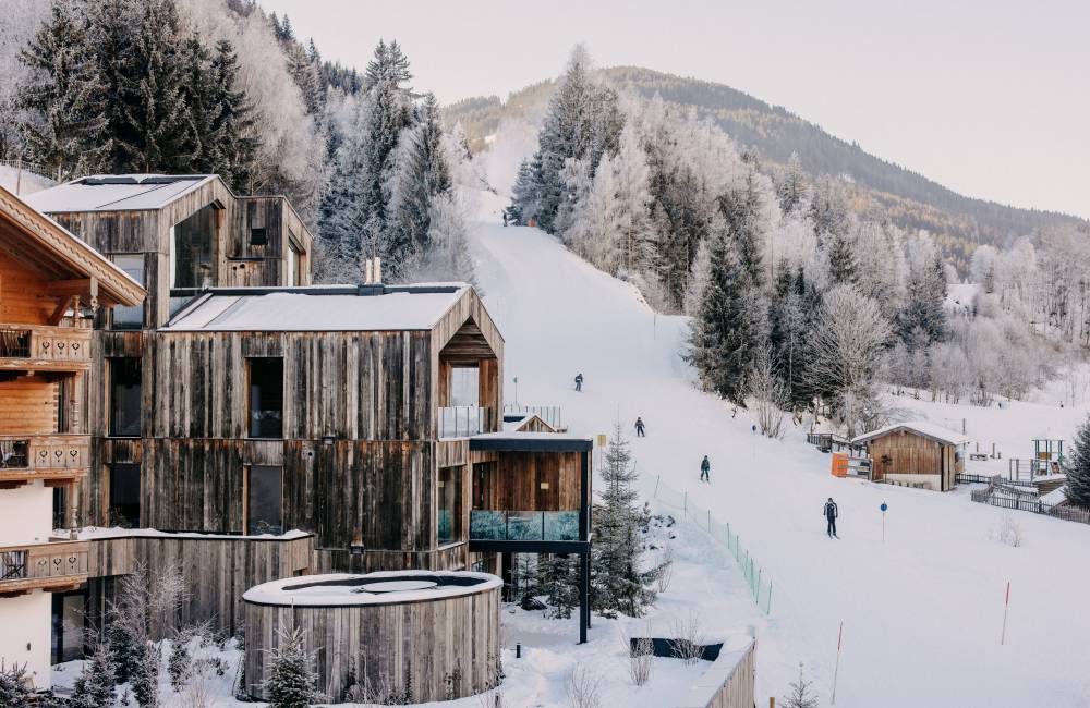 Außenansicht Naturhotel Forsthofgut im Winter mit Skifahrern