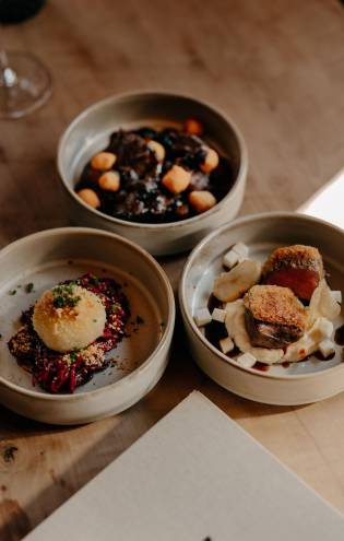 Three plates with food on a wooden table