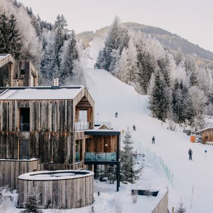 Außenansicht Naturhotel Forsthofgut im Winter mit Skifahrern