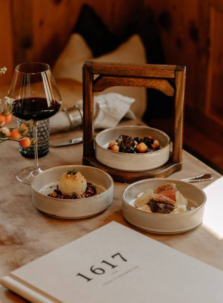 Bauernstube mit traditionellen Speisen auf Holztisch und ein Glas Rotwein