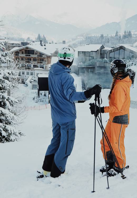 Skifahrer stehen auf der Piste zum Naturhotel Forsthofgut im Winter