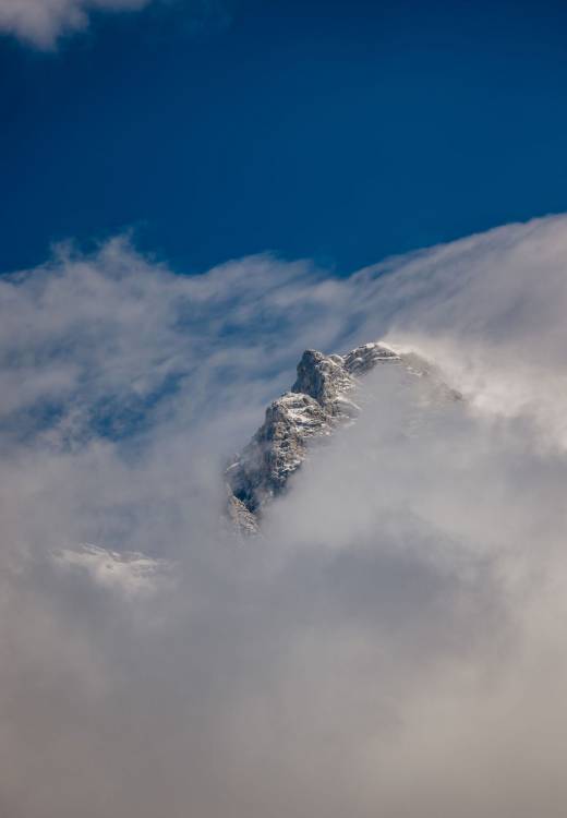 Schneebedeckter Berggipfel in Wolkenwand - Natur i