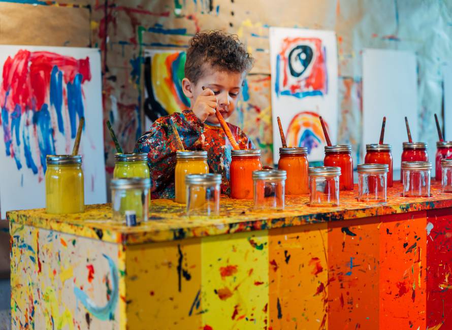 Forsthofgut Art Studio: Child with brush and lots of colours and pictures in the background