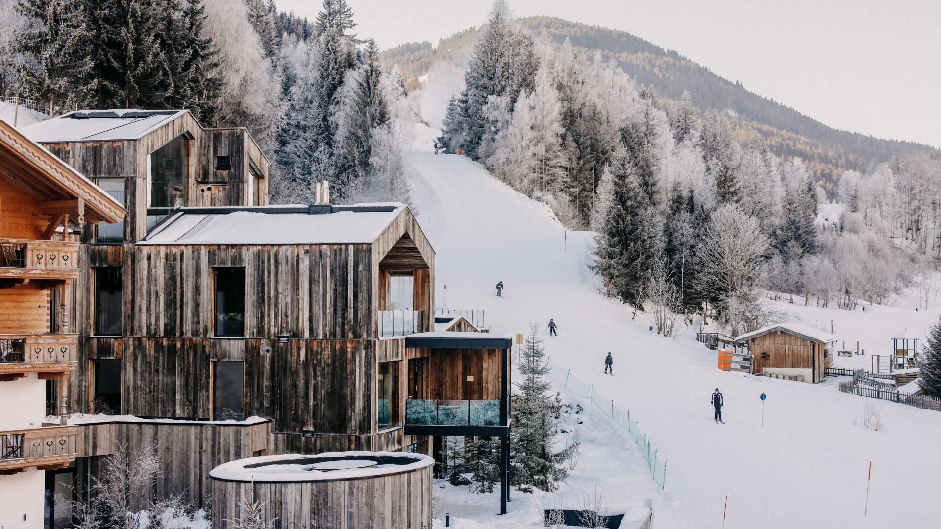 Außenansicht Naturhotel Forsthofgut im Winter mit Skifahrern